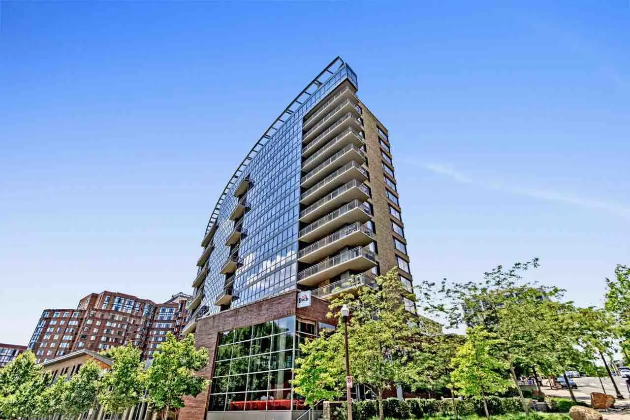 Contemporary glass condominium complex for sale in downtown area surrounded by trees